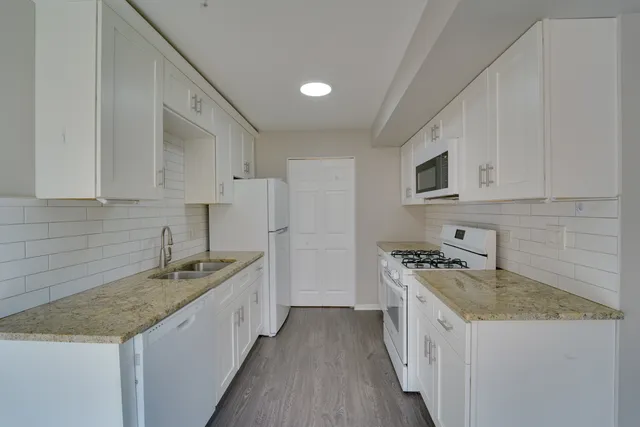 a kitchen with granite countertop a sink a stove and refrigerator