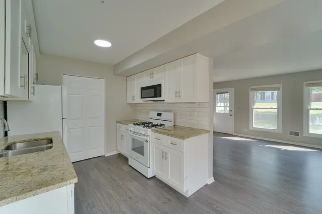 a kitchen with stainless steel appliances granite countertop a stove a sink dishwasher and a refrigerator with wooden floor