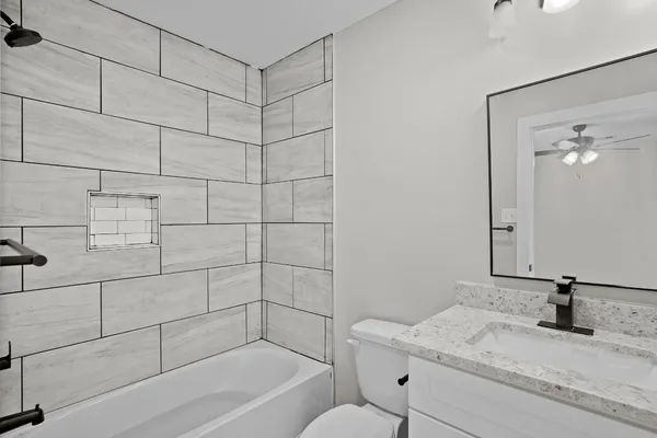 a bathroom with a granite countertop sink a toilet and shower