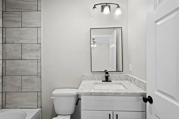 a bathroom with a granite countertop sink a toilet and a mirror