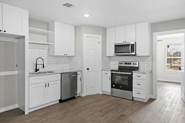 a kitchen with white cabinets stainless steel appliances and wooden floor