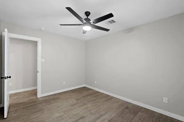 an empty room with wooden floor and ceiling fan