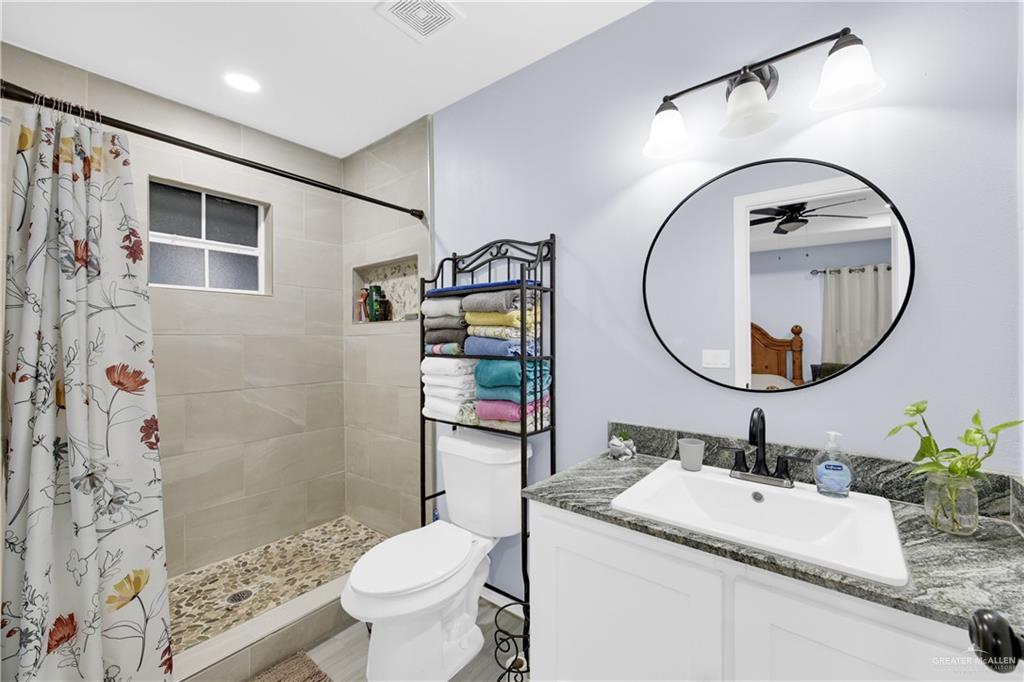 10514 Crocosmia Lane Edcouch, TX 78538 - Photo 13 of 22 a bathroom with a granite countertop toilet a sink and a mirror