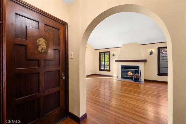a view of an empty room with wooden floor and a fireplace