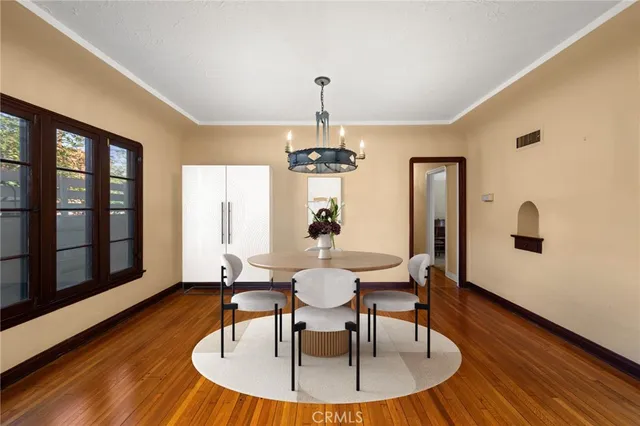 a dining room with wooden floor a chandelier a wooden table and chairs