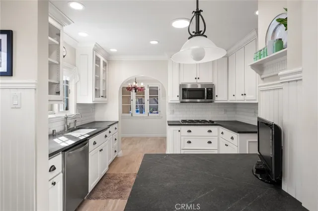 a kitchen with granite countertop a stove top oven a sink a counter space and cabinets