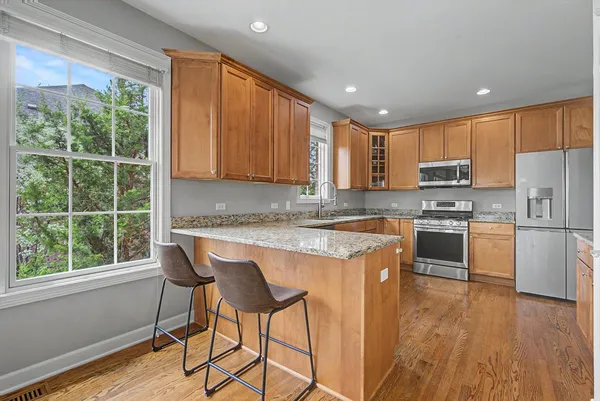 a kitchen with kitchen island granite countertop wooden floors and white stainless steel appliances