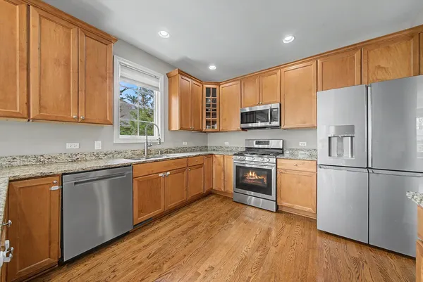 a kitchen with stainless steel appliances granite countertop a refrigerator a stove top oven a sink and dishwasher with wooden floor