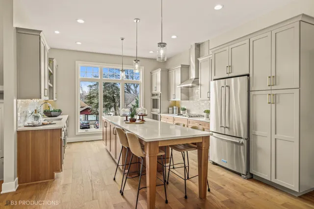 a kitchen with stainless steel appliances a refrigerator a sink dishwasher a stove and white cabinets with wooden floor