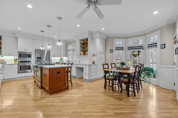 a kitchen with stainless steel appliances granite countertop a stove top oven a sink dishwasher a dining table and chairs with wooden floor