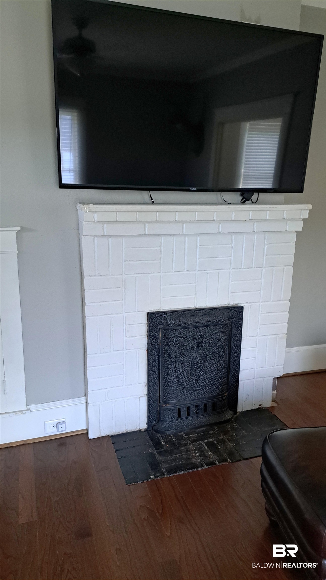 110 South Main Street Evergreen, AL 36401 - Photo 6 of 27 White brick fireplace with an ornate cast iron insert and dark wood-finish flooring