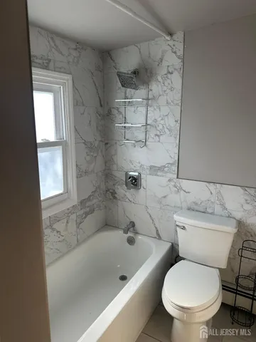 a white toilet sitting next to a bath tub and shower