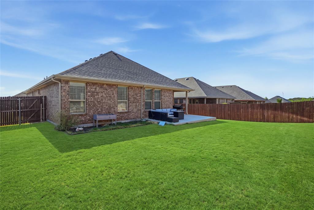1812 Ruffian Road Granbury, TX 76049 - Photo 35 of 37 Brick exterior with pitched roofline and covered patio overlooking expansive manicured lawn