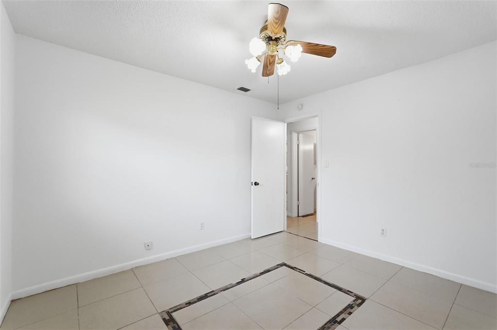 4848 Judy Ann Court Orlando, FL 32808 - Photo 24 of 39 en empty room with chandelier fan and kitchen view