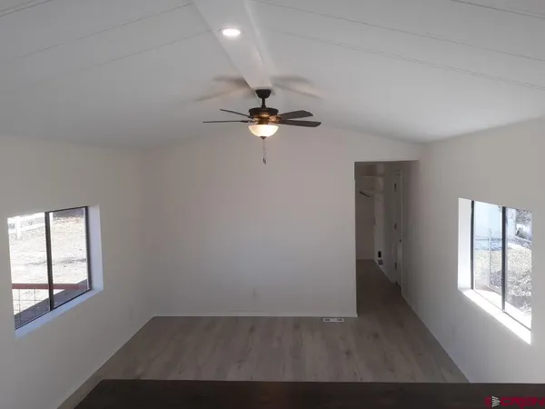 an empty room with windows and ceiling fan