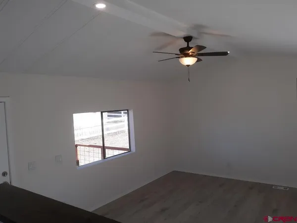 an empty room with a window and a ceiling fan