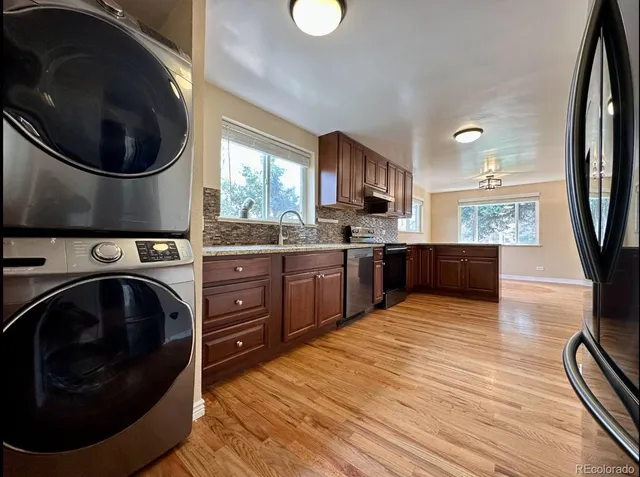 a kitchen with stainless steel appliances granite countertop a sink a stove and a wooden floors