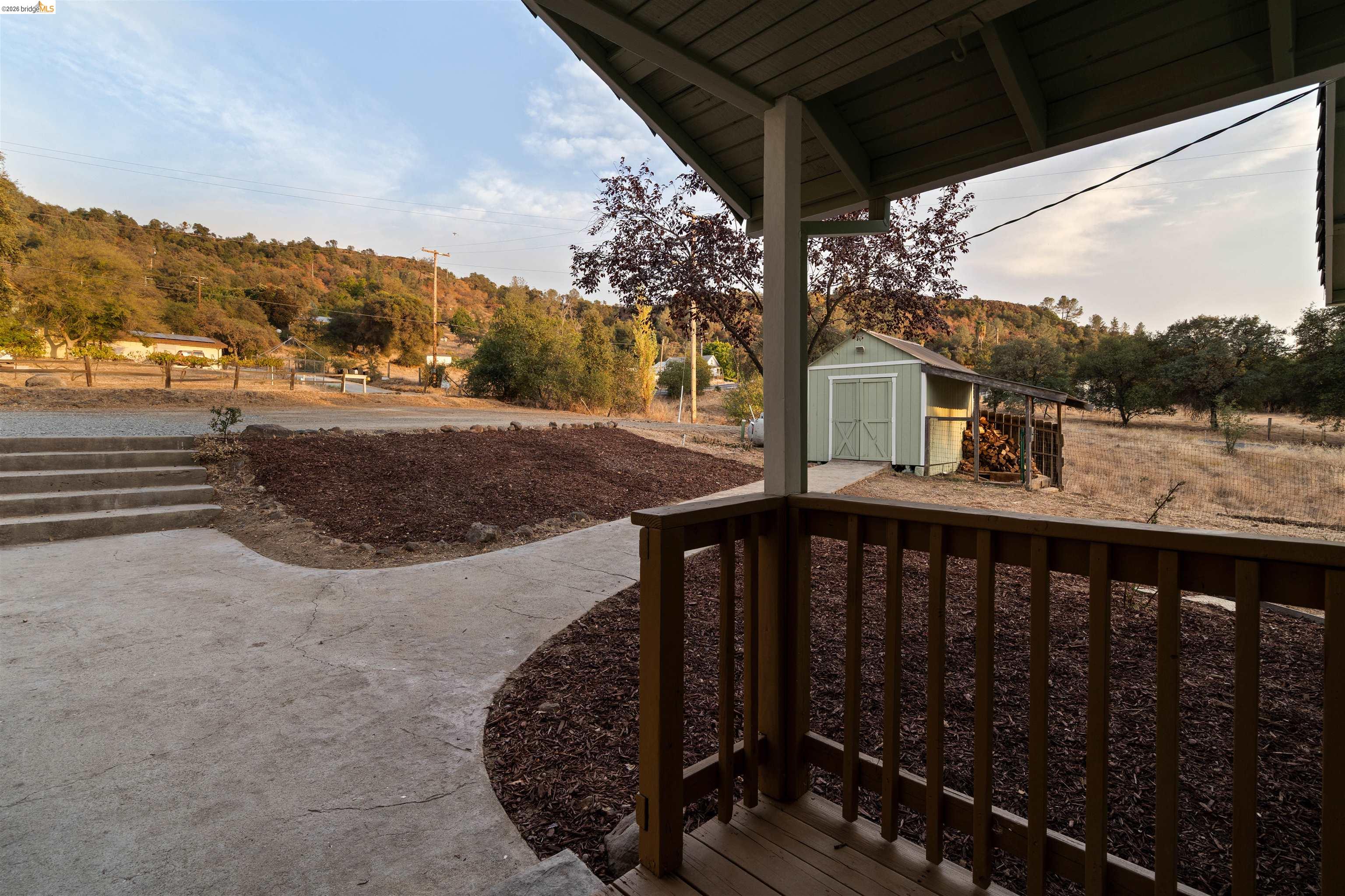 19676 Rawhide Road Sonora, CA 95370 - Photo 42 of 67 Covered porch with wood railing, concrete walkway, and landscaped garden beds