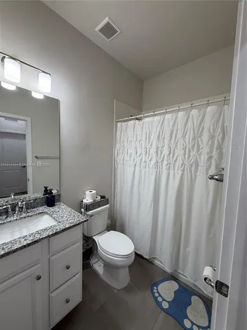 a bathroom with a granite countertop sink toilet a mirror a vanity and shower