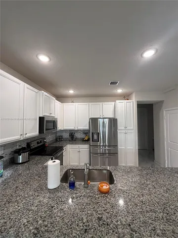 a kitchen with sink a refrigerator and cabinets