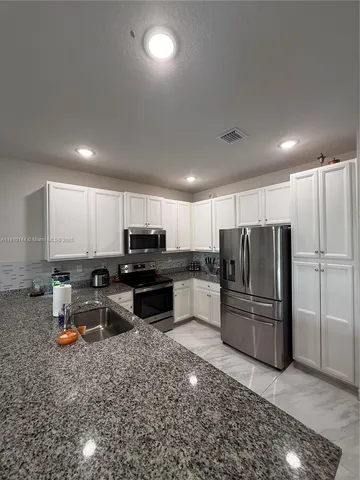 a kitchen with refrigerator and chairs