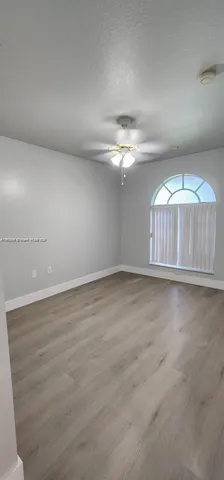 an empty room with chandelier fan and windows