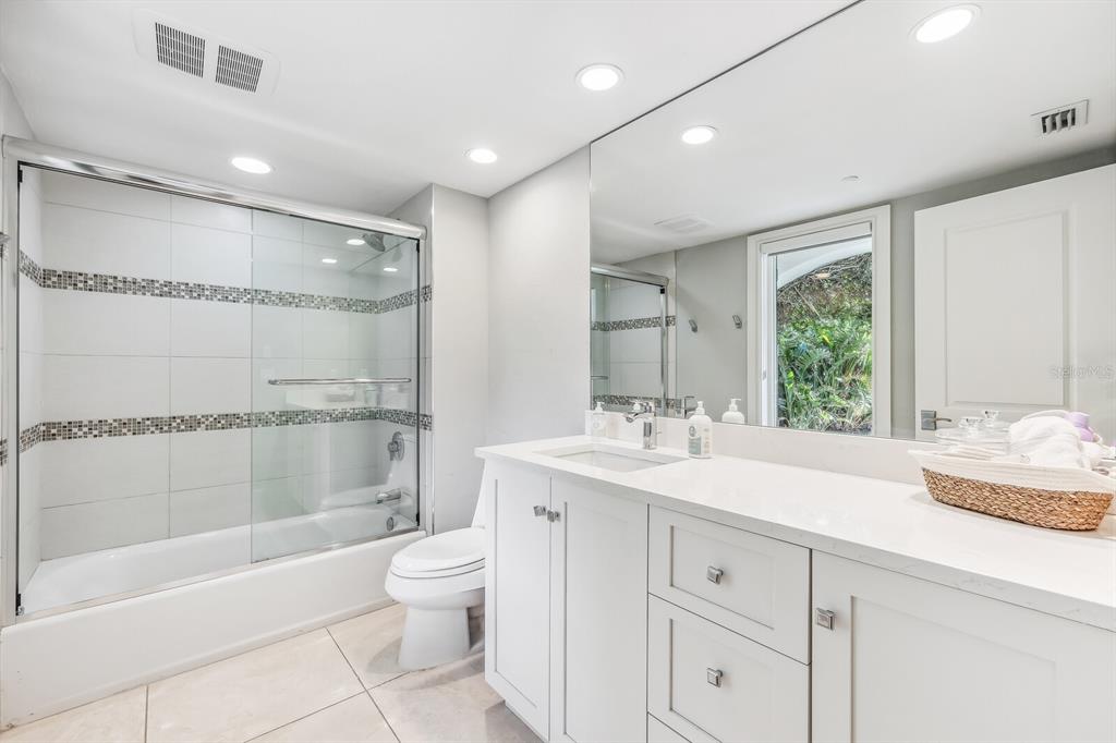 1644 Treasure Lane Boca Grande, FL 33921 - Photo 26 of 42 a bathroom with a granite countertop sink toilet a large mirror a bathtub and shower