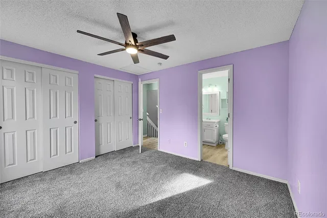 a view of a livingroom with a ceiling fan & windows