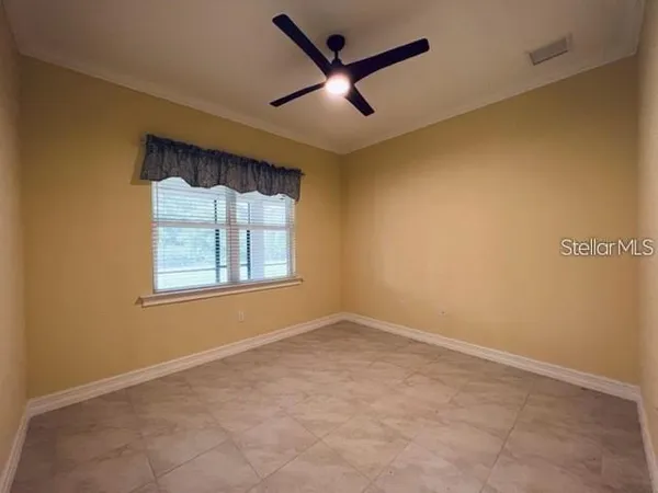 an empty room with windows and ceiling fan