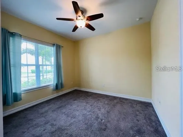 an empty room with windows and ceiling fan