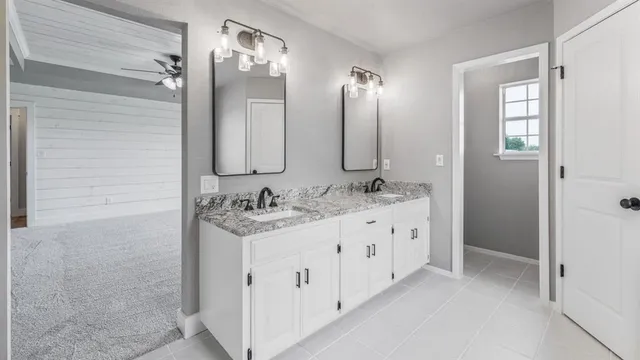 a bathroom with a granite countertop sink a mirror a bathtub and shower