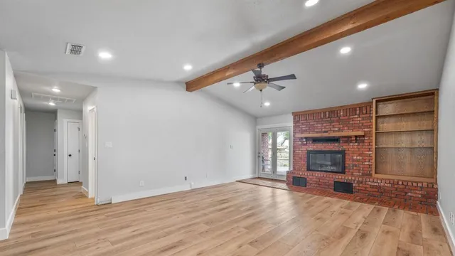 a view of an empty room with a fireplace and a window