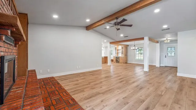 a view of an empty room with window and wooden floor