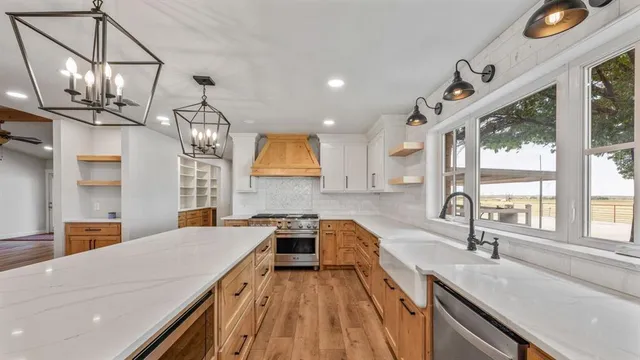 a kitchen with stainless steel appliances granite countertop a sink a stove and a wooden floors