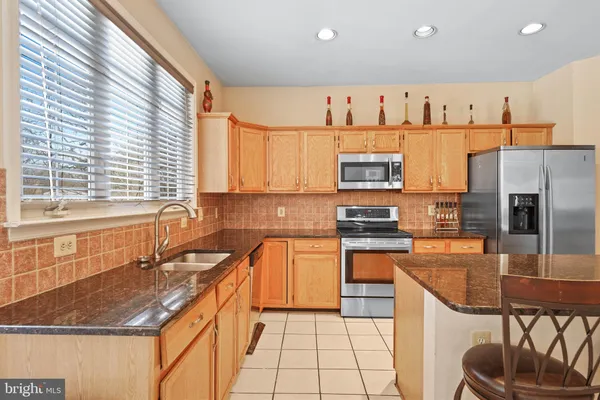 a kitchen with stainless steel appliances granite countertop a refrigerator a stove and a sink with wooden floor
