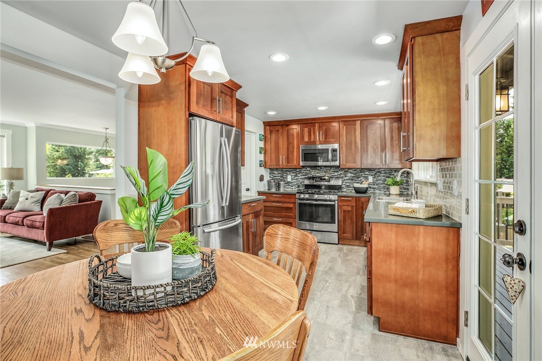 21910 1st Place West Bothell, WA 98021 - Photo 8 of 33 a kitchen with stainless steel appliances granite countertop a refrigerator a stove a sink dishwasher and a dining table with garden view