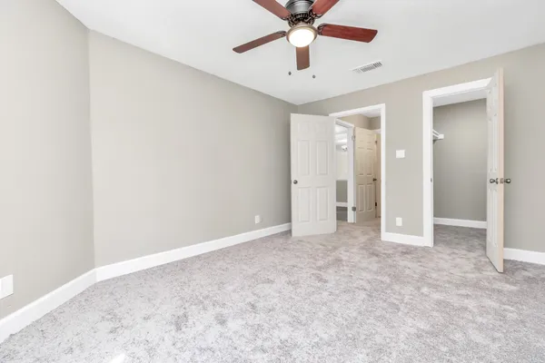 an empty room with closet and a chandelier fan