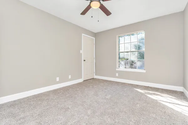 an empty room with windows and ceiling fan
