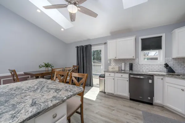 a kitchen with a stove a sink dishwasher a dining table and chairs with wooden floor