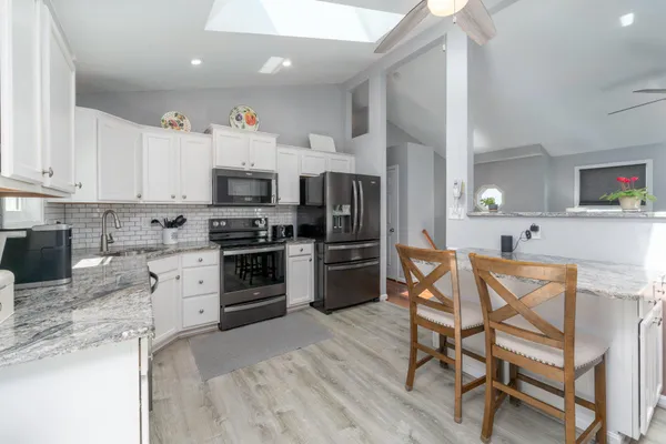 a kitchen with stainless steel appliances a stove a sink dishwasher a refrigerator and a dining table with wooden floor