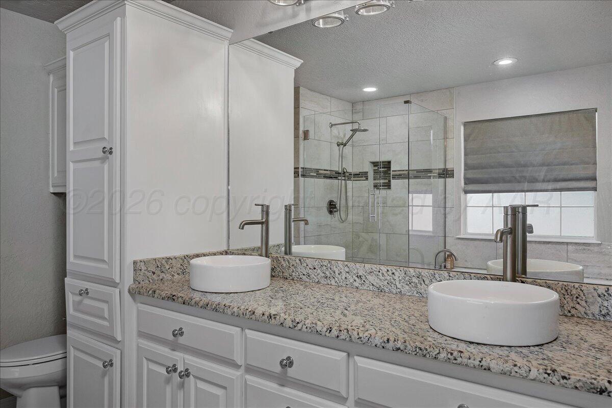 8910 Dove Road Canyon, TX 79015 - Photo 24 of 47 a bathroom with a granite countertop sink a toilet and shower
