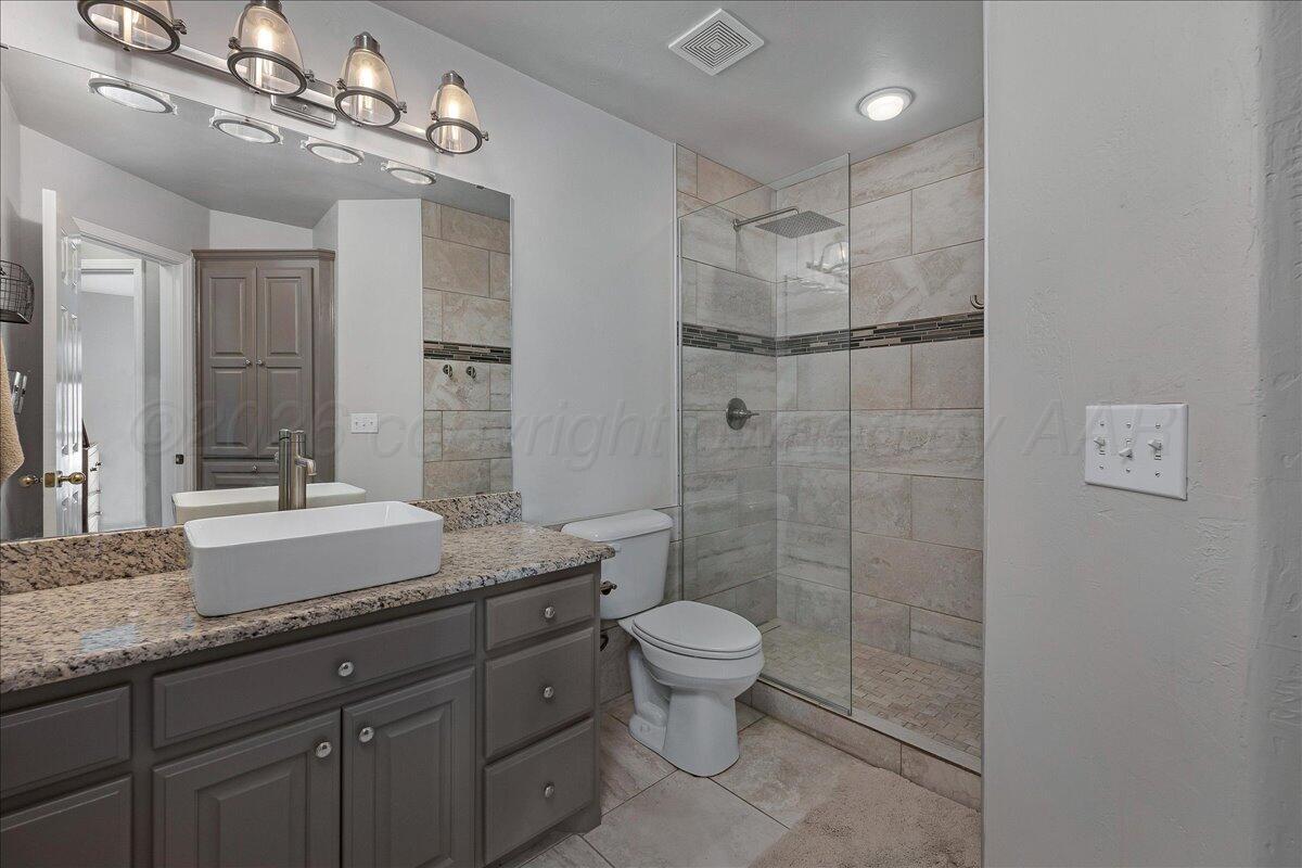 8910 Dove Road Canyon, TX 79015 - Photo 28 of 47 a spacious bathroom with a granite countertop sink a toilet a mirror and shower