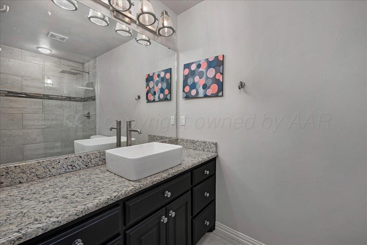 8910 Dove Road Canyon, TX 79015 - Photo 30 of 47 a bathroom with a granite countertop sink a mirror and vanity