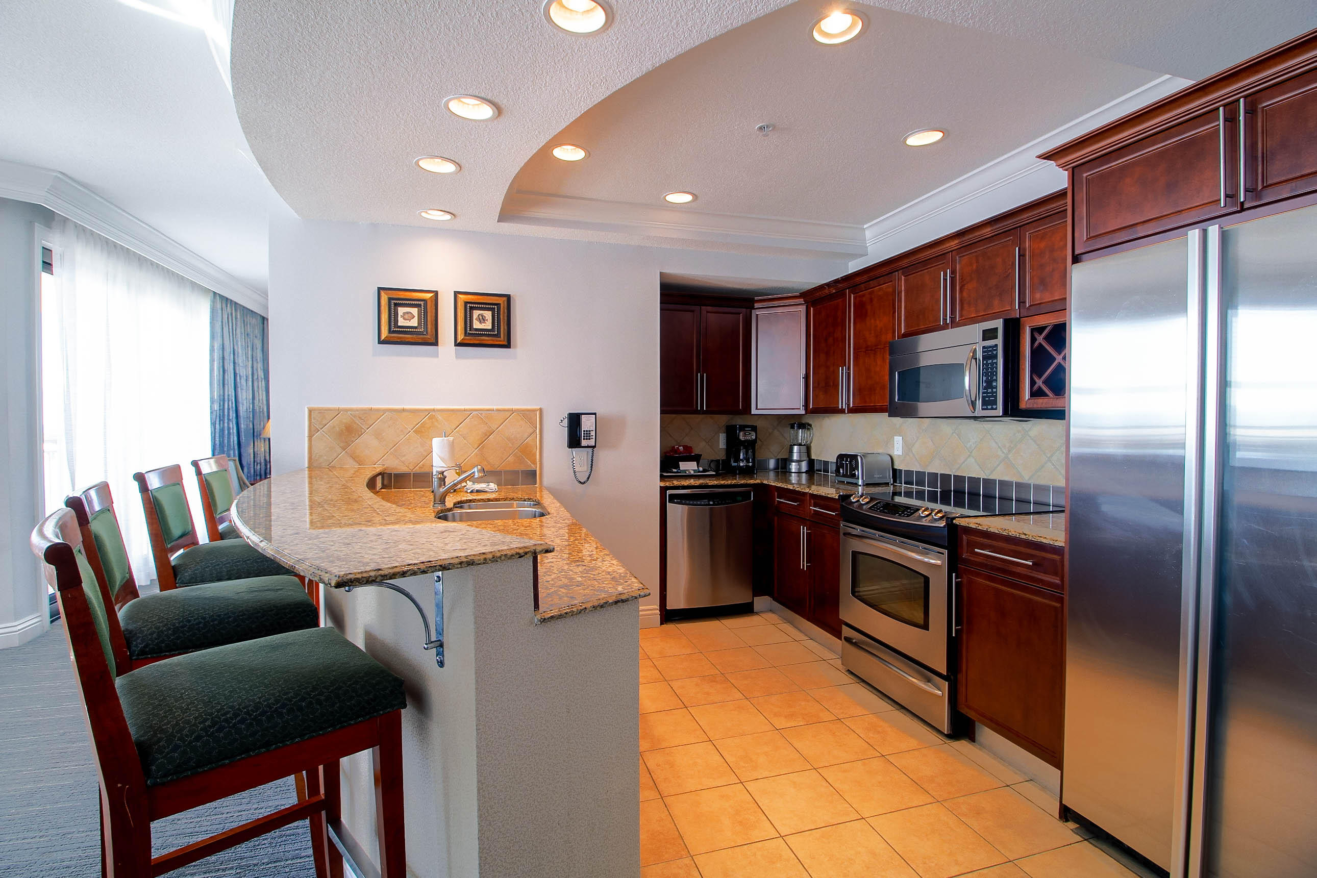 10 Harbor Boulevard, Unit E305E Destin, FL 32541 - Photo 6 of 33 a kitchen with stainless steel appliances granite countertop a refrigerator a stove a sink a dining table and chairs with wooden floor