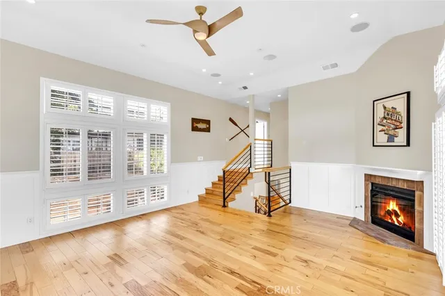 a view of a livingroom with wooden floor a ceiling fan and windows