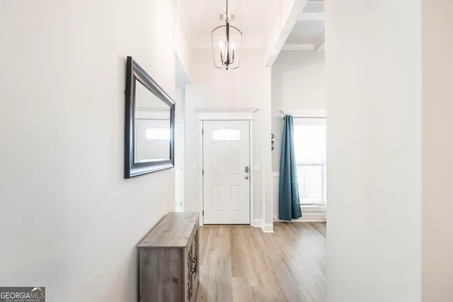 a view of hallway with chandelier fan and wooden floor