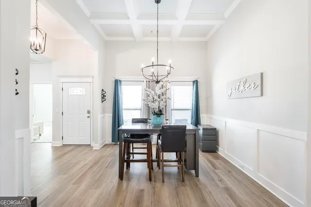 a dining room with wooden floor a chandelier a wooden table and chairs