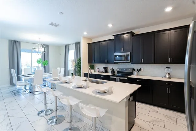 a kitchen with stainless steel appliances a stove a sink a microwave and a refrigerator