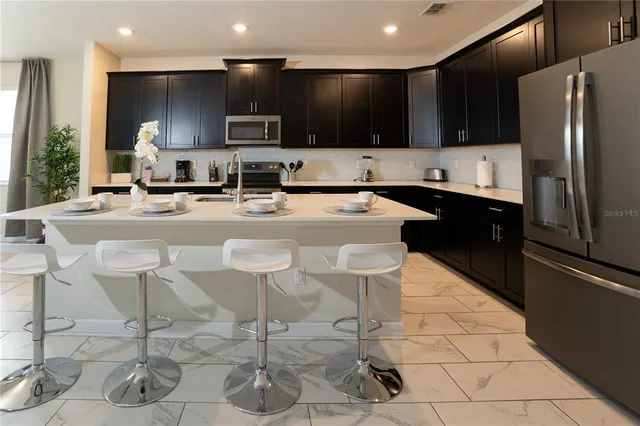 a kitchen with a sink a stove a refrigerator and chairs