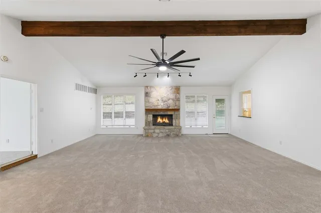 a view of an empty room with a fireplace and a ceiling fan